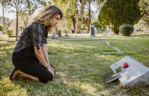 Woman kneeling grave with flower