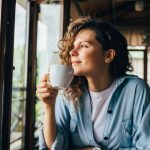 Woman drinking coffee by a window
