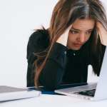 Woman staring at a laptop with her hands in her hair