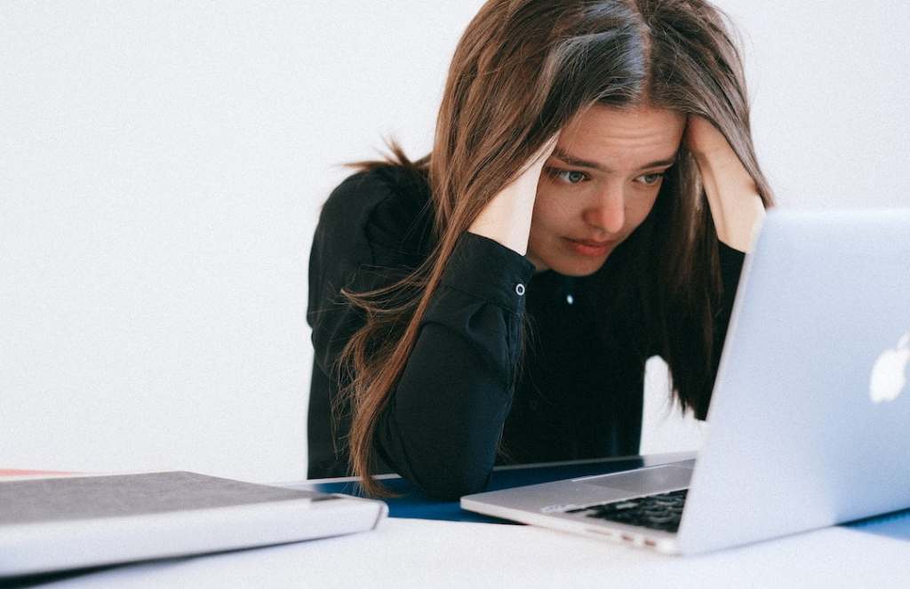 Woman staring at a laptop with her hands in her hair