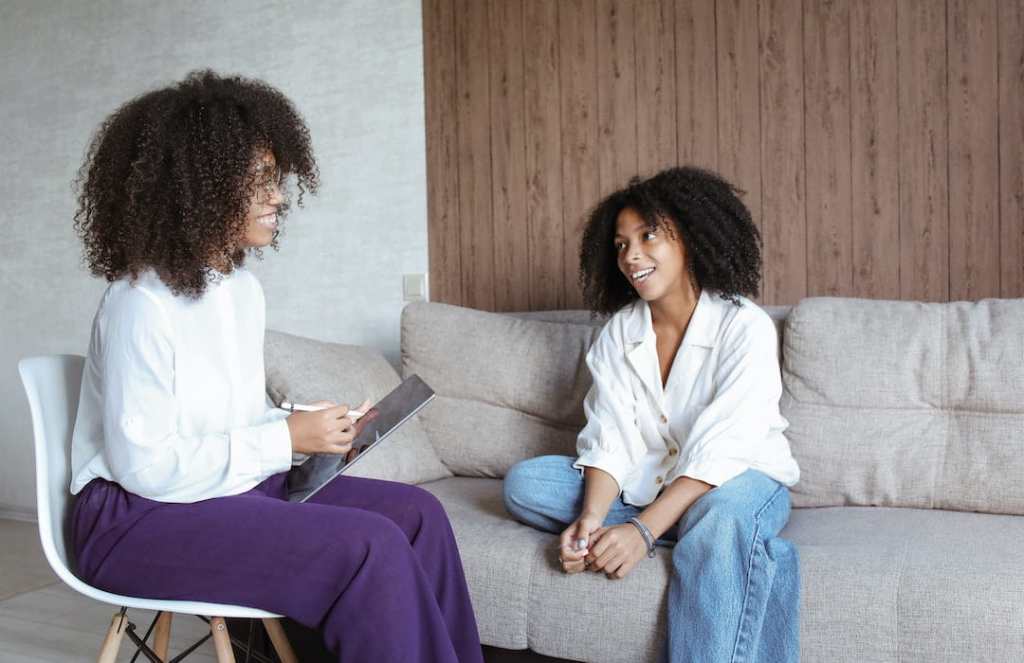a therapist and client sitting together wear white and discussing treatment options