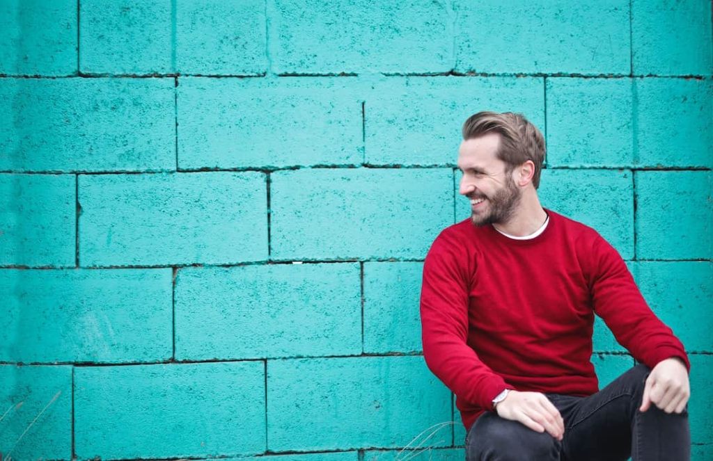 Man in a red shirt sitting by blue wall