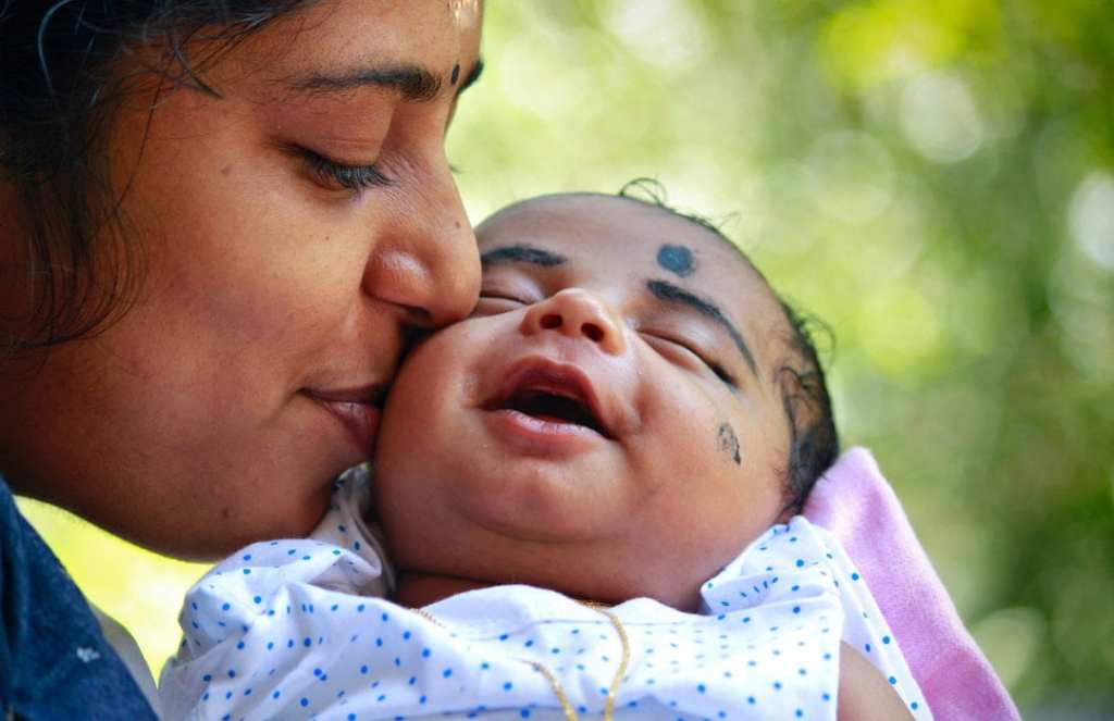 Mother holding and kissing baby