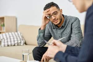 Man speaking to someone with hand on head