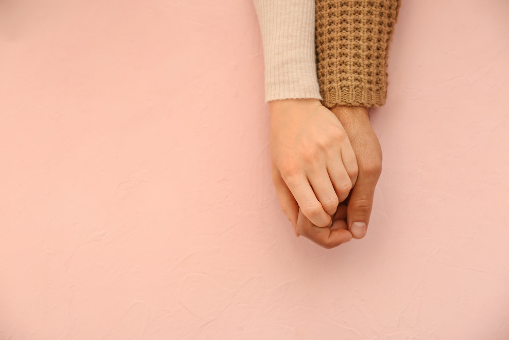 People holding hands against pink background