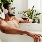 Man listening to music and drinking wine in the bathtub