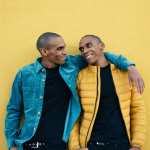 Twin African American brothers posing together against yellow background