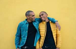 Twin African American brothers posing together against yellow background