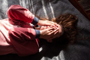 Woman laying on floor with hands over her face, feeling embarrassed