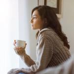 Hispanic woman looking forlorn in a sweater on the couch