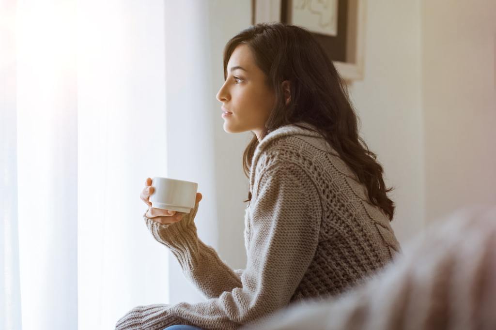 Hispanic woman looking forlorn in a sweater on the couch