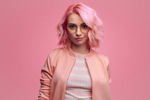 Confident woman with pink hair and jacket facing forward