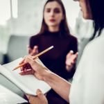 Woman talking to a therapist with a notebook