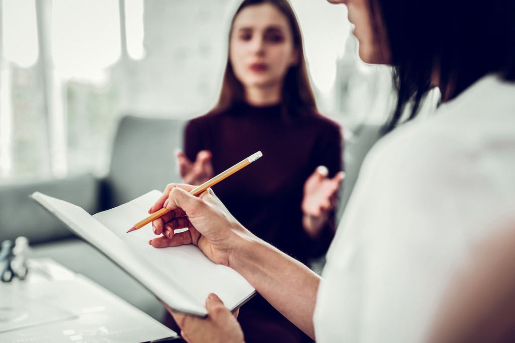 Woman talking to a therapist with a notebook