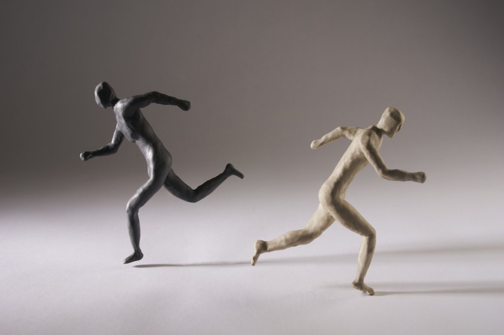 Black and white clay figurines running in opposite directions