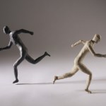 Black and white clay figurines running in opposite directions