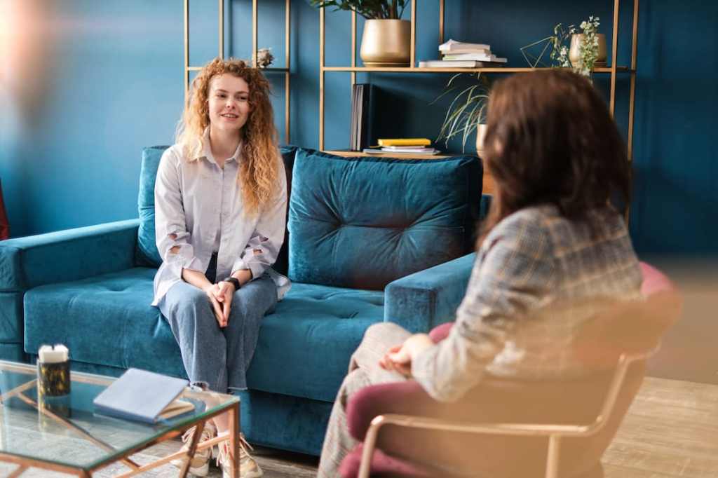 Happy white woman talking to her therapist on a blue couch