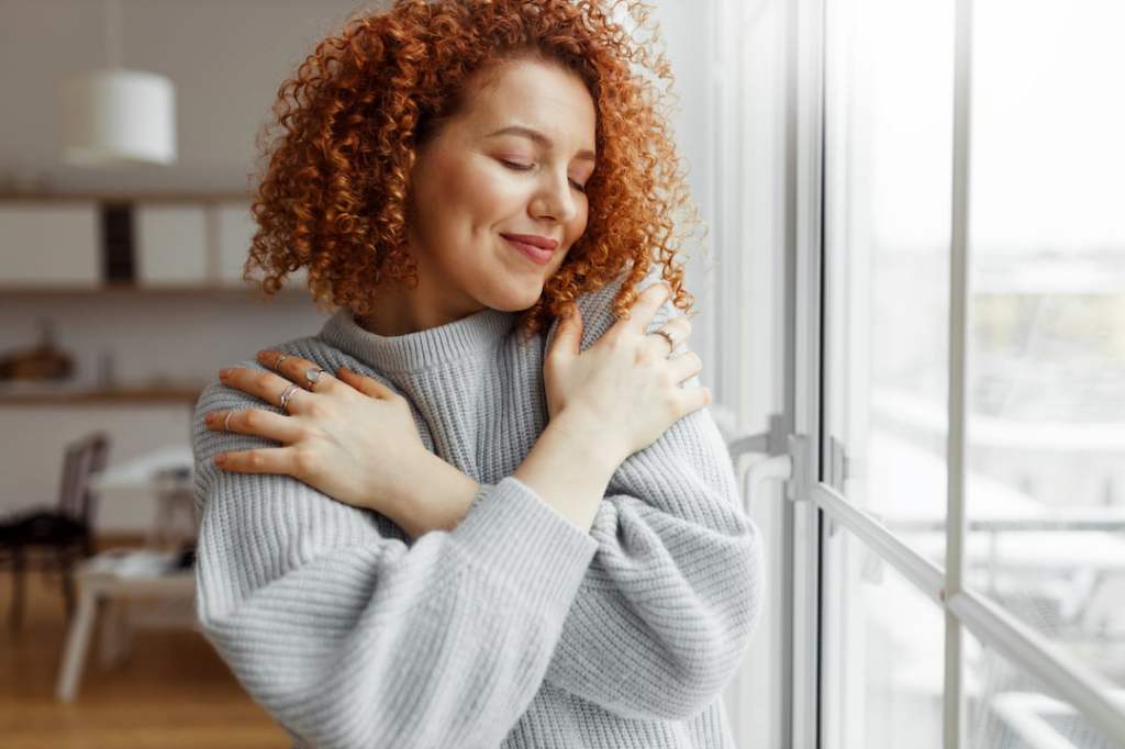 Woman with red hair hugging herself