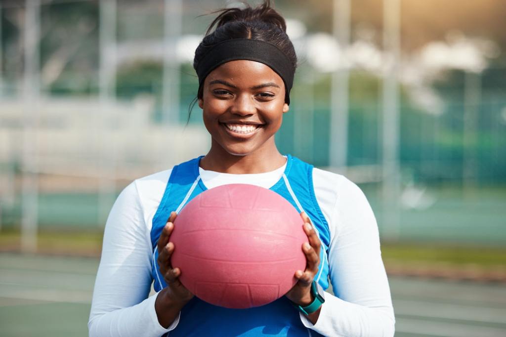 Black college athlete holding ball while wearing blue jersey