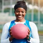 Black college athlete holding ball while wearing blue jersey