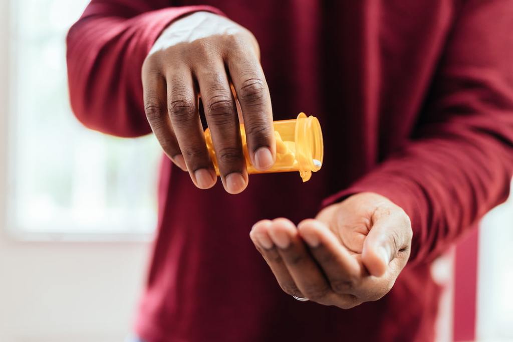 Person taking pills out of pill bottle