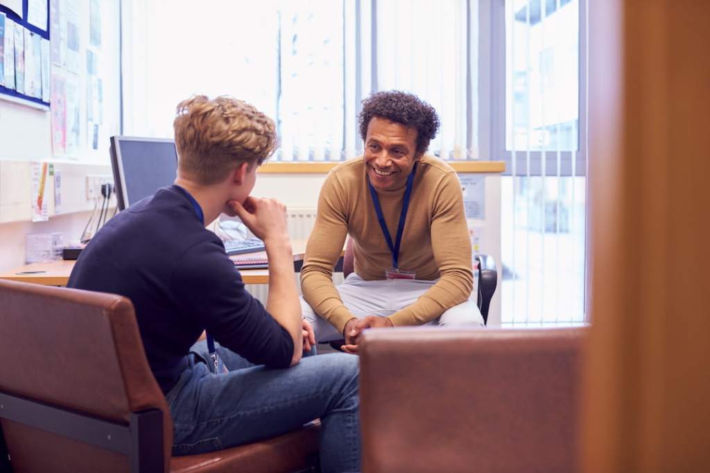 Male college student meeting with counselor during therapy session