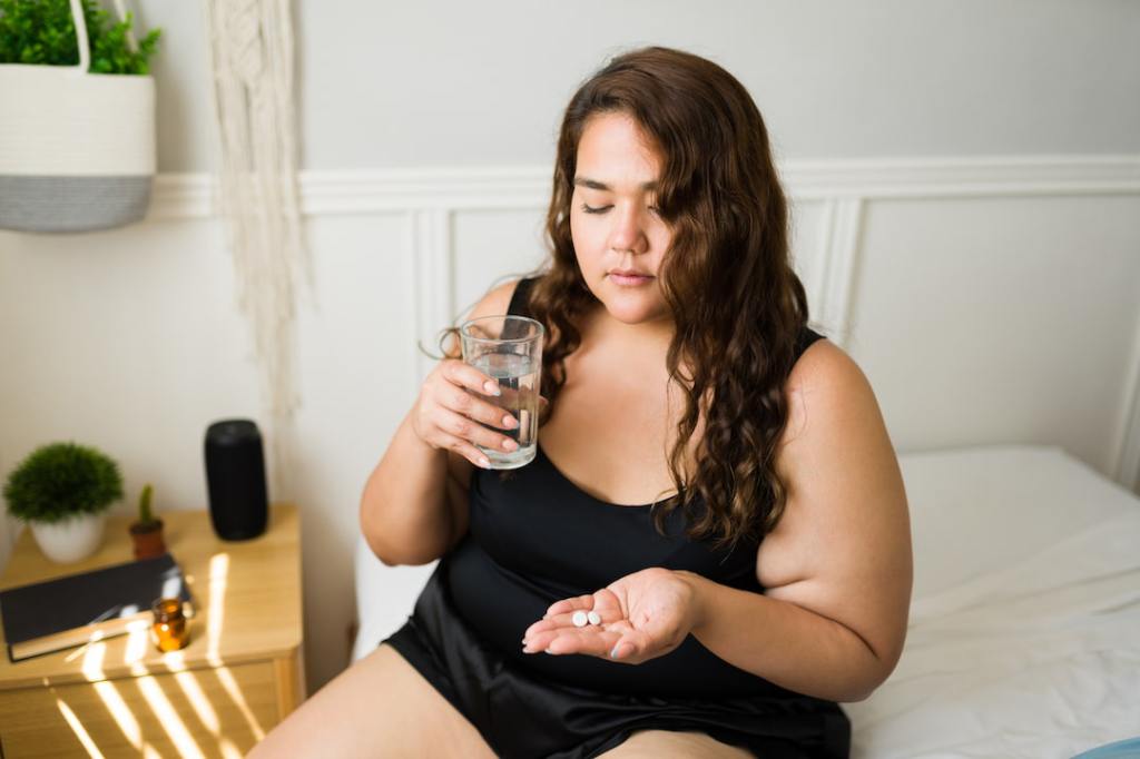 Woman sitting on a bed taking medication