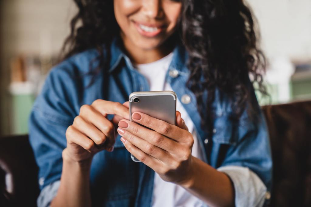 Smiling woman in a jean jacket spending time on her smartphone