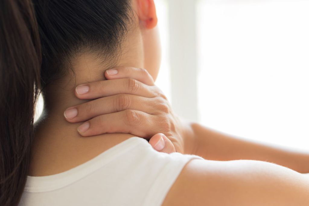 Woman touching her sore neck muscles in pain
