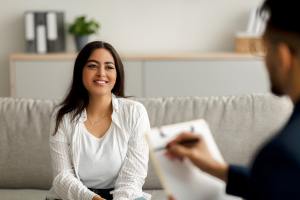 Woman in a white shirt on a cream couch speaking with a male therapist