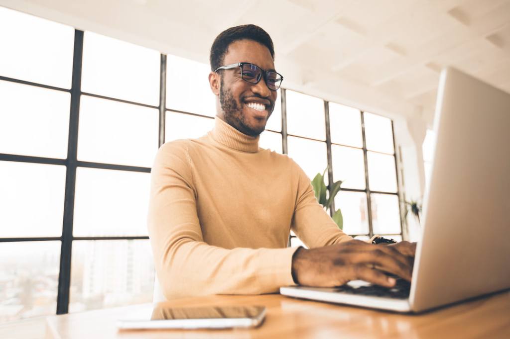 Happy man in a turtleneck checking his email on the computer