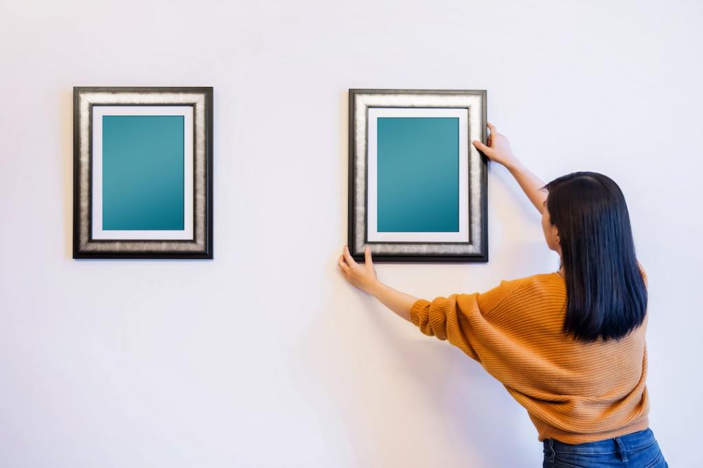 Woman hanging and adjusting pictures