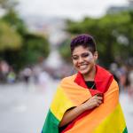 Queer individual wearing a Pride flag