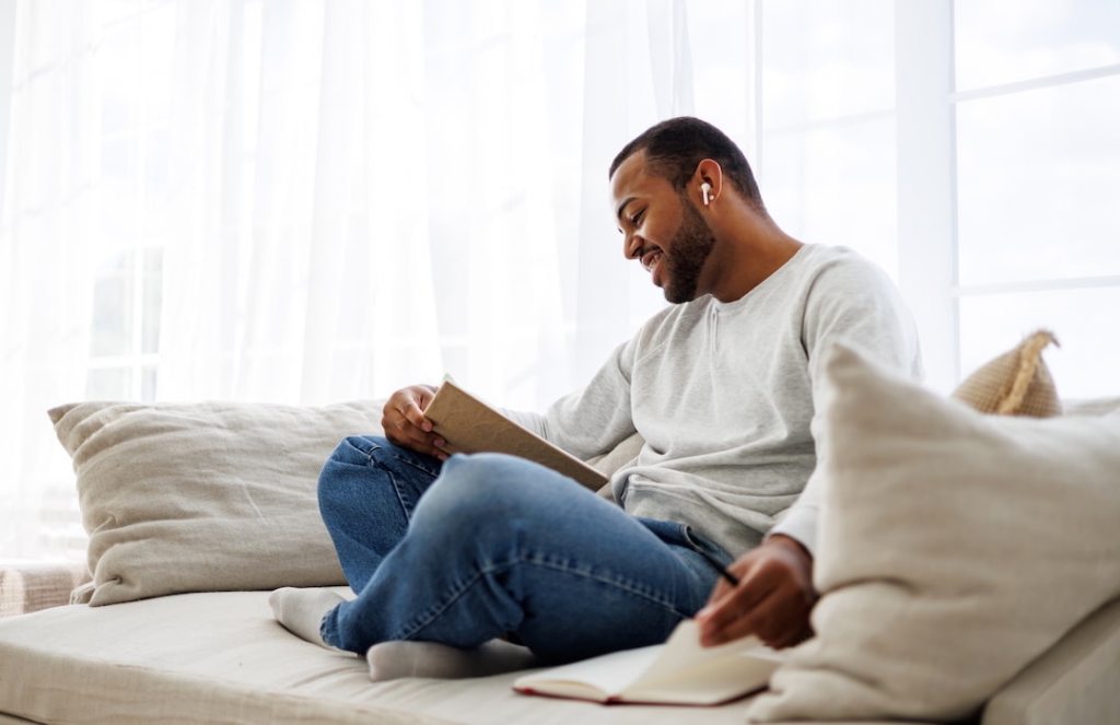 Black man reading book in his living room