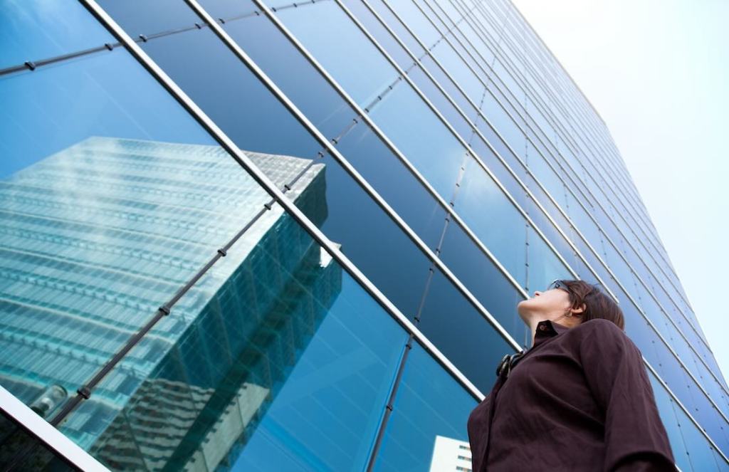 Business woman looking up at skyscraper