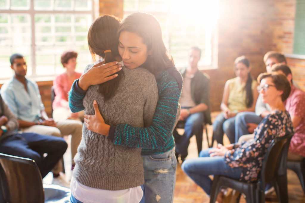 Two women hugging in group therapy