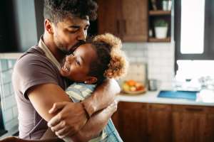 Man hugging his daughter in a kitchen