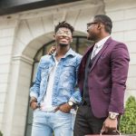 Two young and stylish African American men in the city smiling and talking. father and adult son relationship