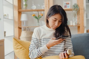 Woman holding prescription medication bottle and her phone