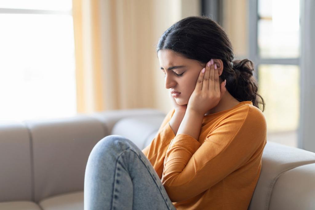 Woman on a couch covering her ears