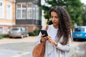 Young woman walking outside looking at her phone