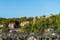 Hill with trees and old brick houses with a bridge.