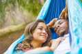 Woman and man cuddling in a blue hammock outdoors