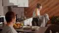Woman putting a sweater on in the kitchen while on the phone
