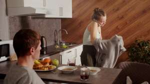 Woman putting a sweater on in the kitchen while on the phone
