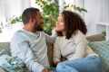 Man and woman sitting on a gray couch talking