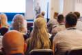 Blonde woman sat with other businesspeople at a business conference