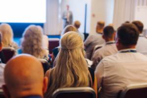 Blonde woman sat with other businesspeople at a business conference
