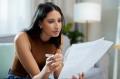 Woman looking through paperwork with a pen on her couch