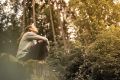 Woman breathing deeply on a rock in the forest